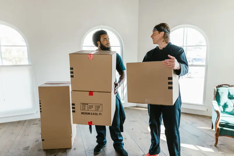 Zwei Helfer mit Kartons in einer Altbauwohnung