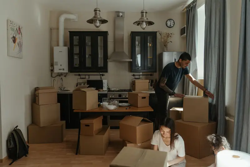 Zwei Personen packen Küche und Wohnbereich in Kartons
