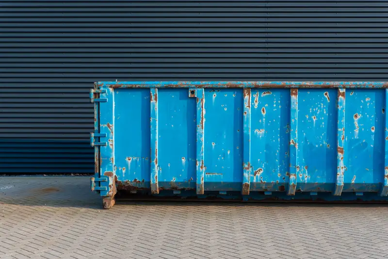 Blauer Entsorgungscontainer vor einer Halle