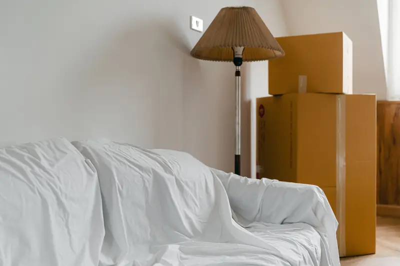 Abgedecktes Sofa und Kartons in einer Wohnung vor der Übergabe