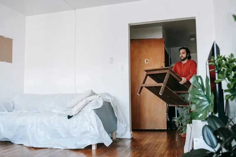 Mann trägt einen Tisch aus der Wohnung