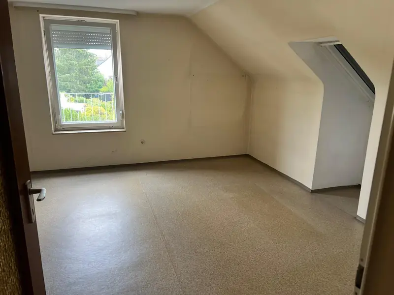 Leeres Dachzimmer mit Fenster nach der Räumung