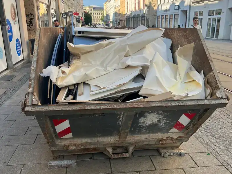 Befüllter Entsorgungscontainer in einer Fußgängerzone