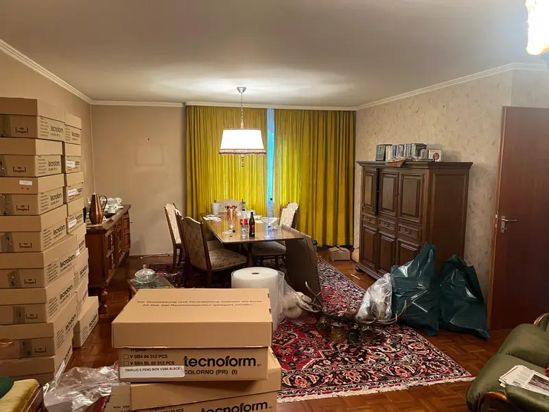 Wohn- und Esszimmer voller Möbel und Umzugskartons vor der Haushaltsauflösung