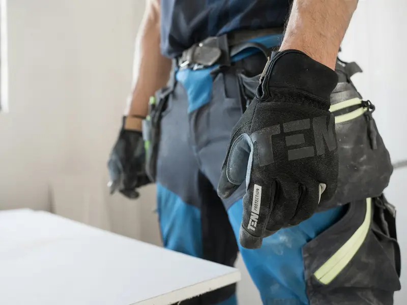 Handwerker in Arbeitskleidung mit Schutzhandschuhen