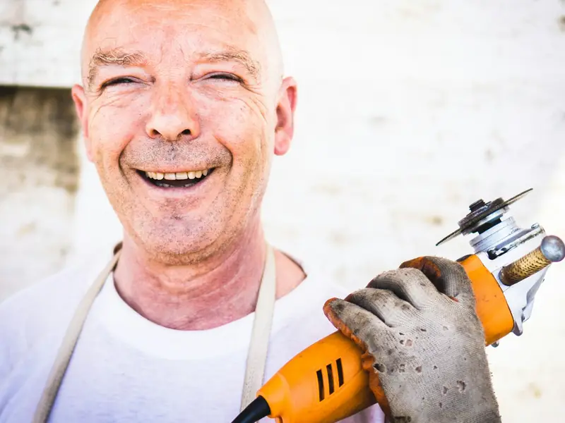 Gut gelaunter Handwerker mit Arbeitshandschuh und Winkelschleifer